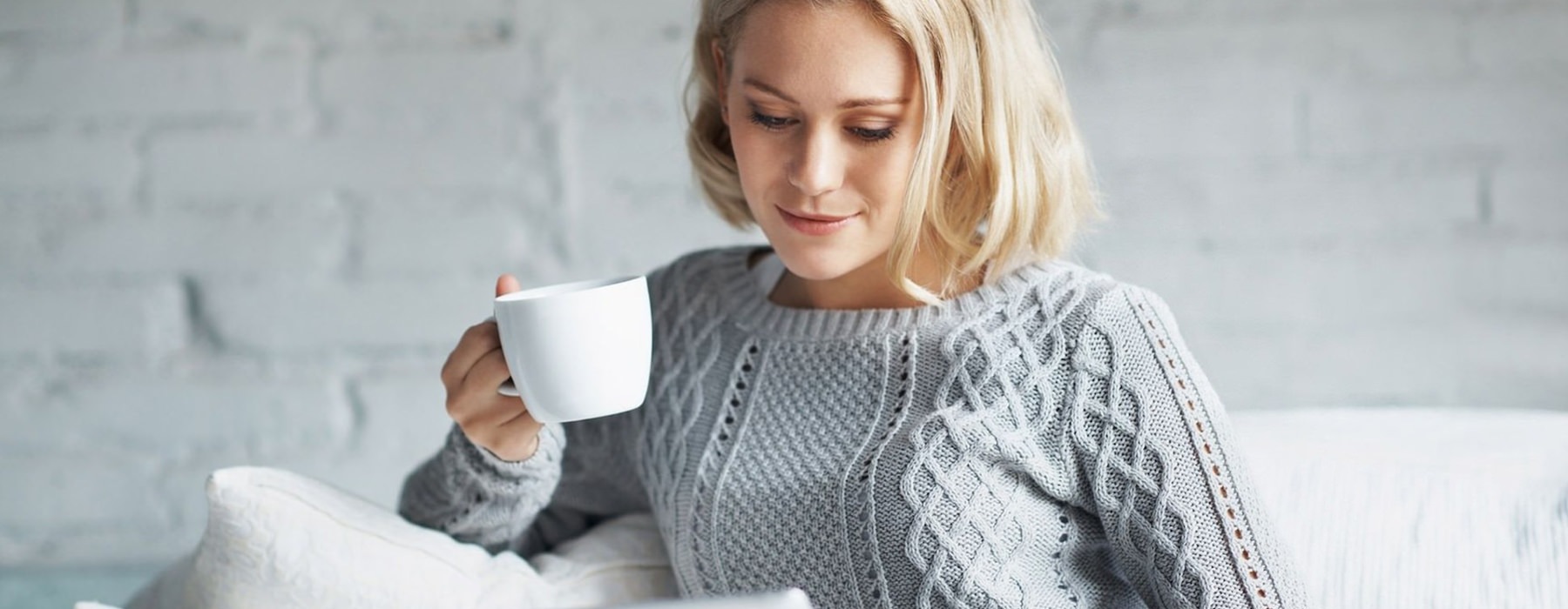 Woman sitting in a living room drinking coffee