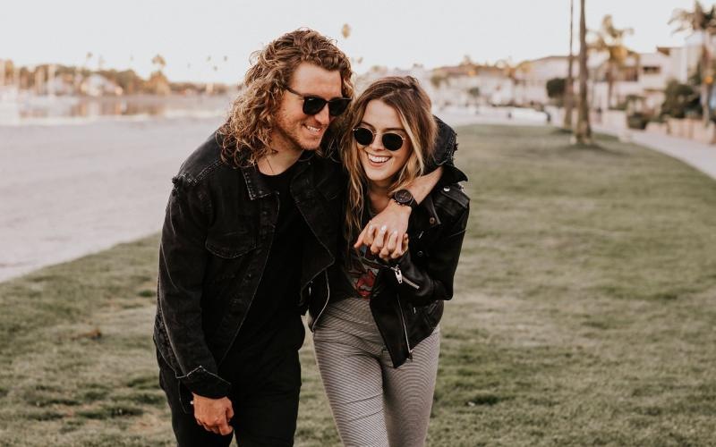Close to the center of everything a couple walks on grassy area in open neighborhood lot